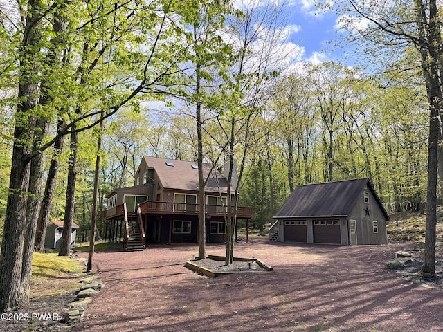 view of front of house with an outdoor structure, stairway, a detached garage, and a wooden deck