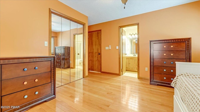 bedroom featuring light wood-type flooring, ensuite bathroom, baseboards, and a closet