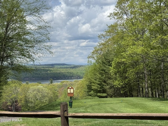 view of property's community with a forest view, a water view, and a yard