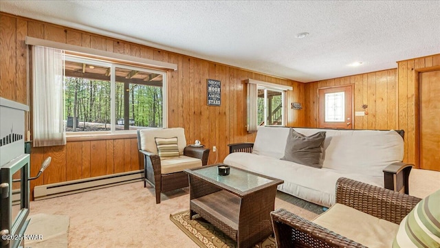 carpeted living room featuring a baseboard heating unit, wood walls, and a textured ceiling