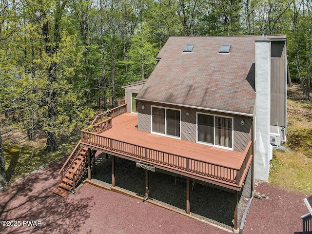 back of property with a wooden deck, stairway, a chimney, a shingled roof, and cooling unit