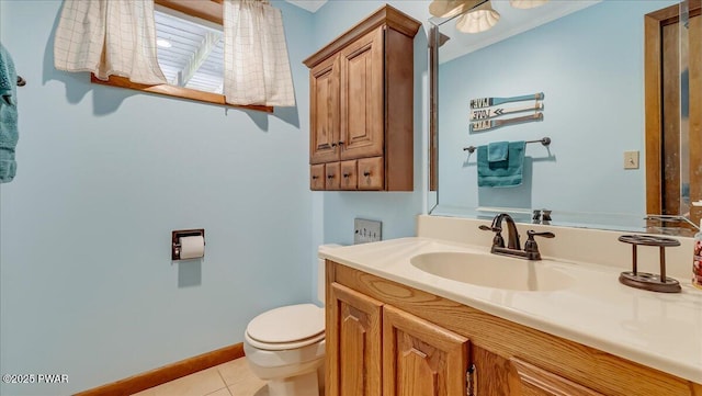 half bath with toilet, tile patterned flooring, vanity, and baseboards