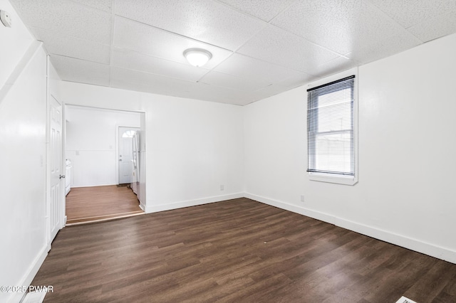 unfurnished room with dark hardwood / wood-style floors and a drop ceiling