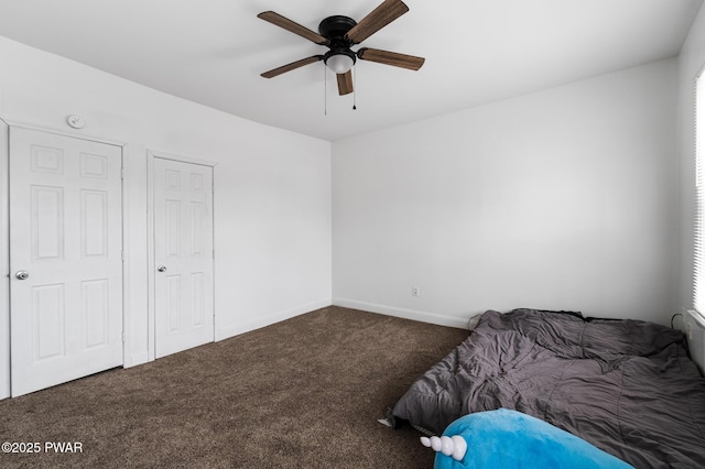 unfurnished bedroom with ceiling fan and dark carpet