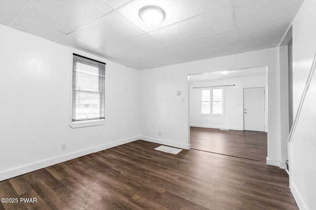 spare room with a paneled ceiling and dark hardwood / wood-style floors