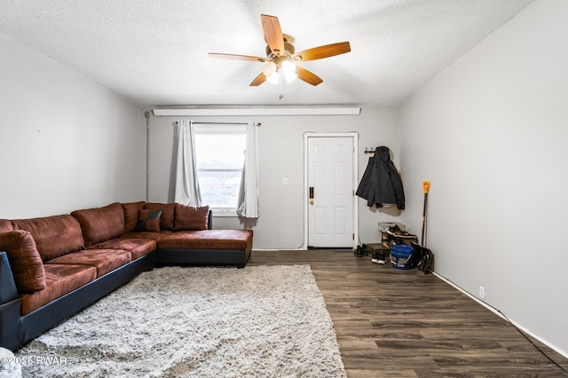 living room with ceiling fan, dark hardwood / wood-style flooring, and a textured ceiling