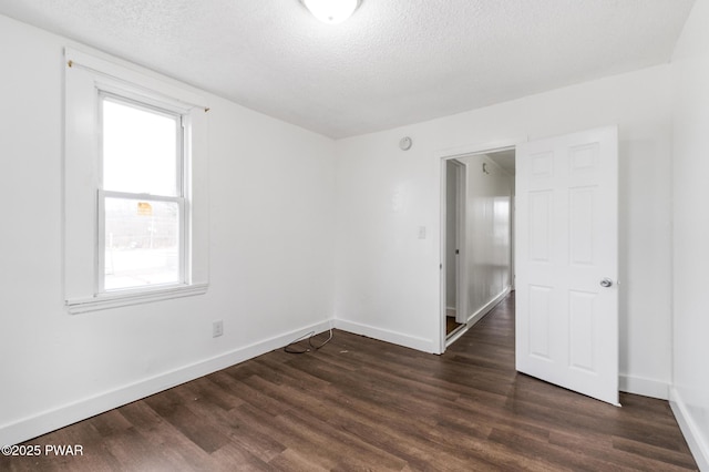 spare room with plenty of natural light, dark hardwood / wood-style floors, and a textured ceiling