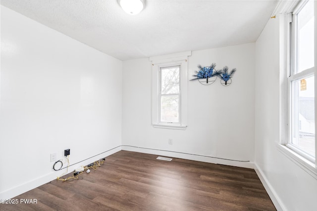 unfurnished room featuring a textured ceiling and dark hardwood / wood-style floors