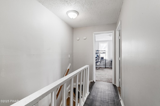 corridor featuring dark carpet and a textured ceiling