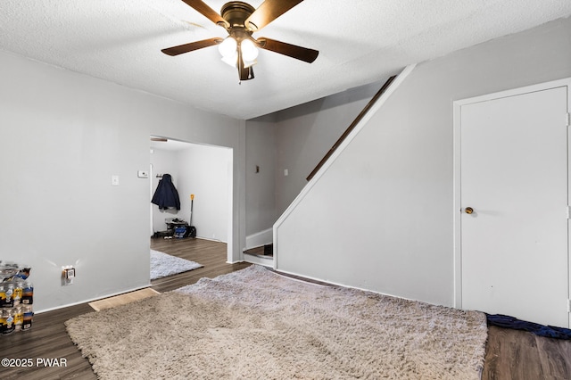 interior space with ceiling fan, dark hardwood / wood-style flooring, and a textured ceiling