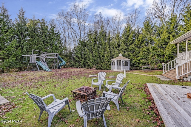 view of yard featuring a playground, a deck, and an outdoor fire pit