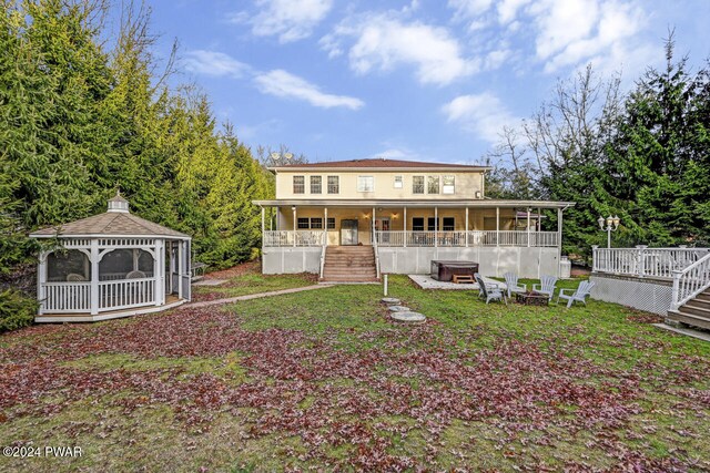 back of property with a gazebo and an outdoor fire pit