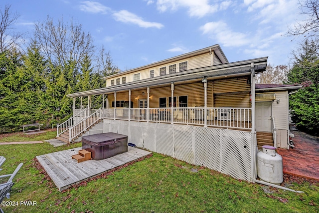 back of property featuring a hot tub and a lawn