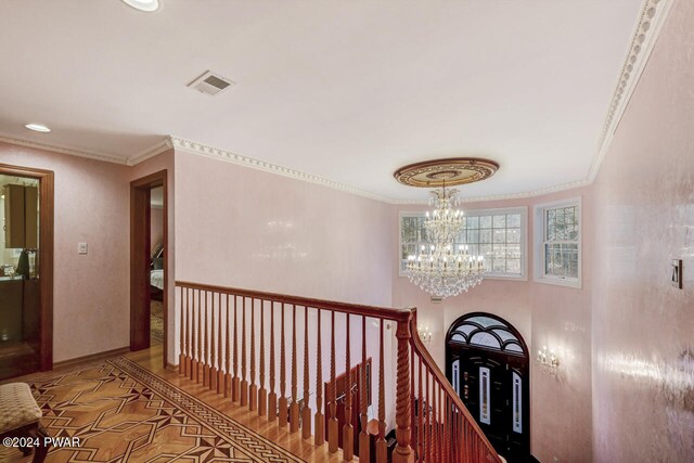 corridor featuring ornamental molding and an inviting chandelier