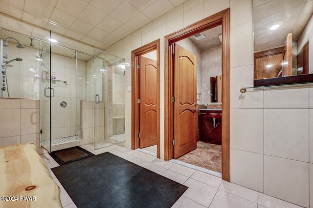 bathroom featuring tile patterned floors, a shower with shower door, and tile walls