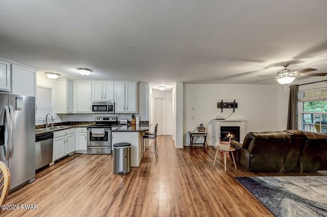 kitchen with white cabinetry, sink, ceiling fan, a breakfast bar area, and appliances with stainless steel finishes