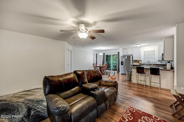 living room featuring wood-type flooring, ceiling fan, and sink