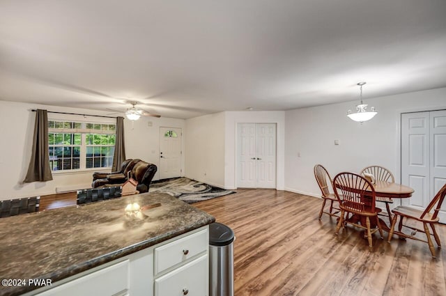 kitchen featuring ceiling fan, dark stone countertops, light hardwood / wood-style floors, decorative light fixtures, and white cabinets