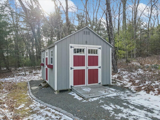 snow covered structure featuring a storage unit and an outdoor structure