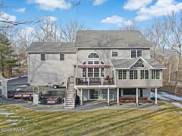 back of house featuring a lawn, a deck, a patio, a sunroom, and stairs