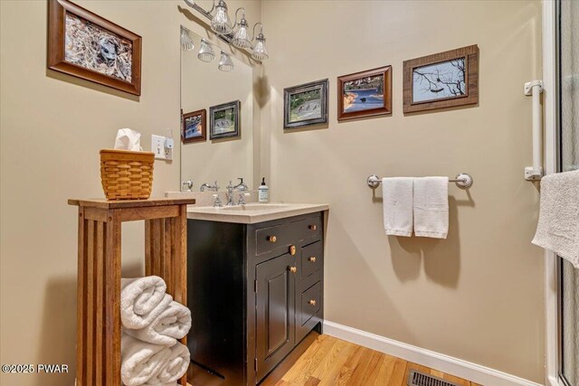 bathroom featuring visible vents, baseboards, wood finished floors, and vanity