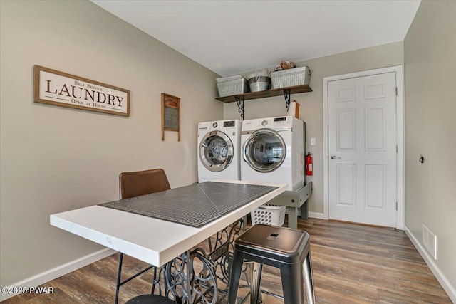 laundry area featuring visible vents, baseboards, wood finished floors, and washer and clothes dryer