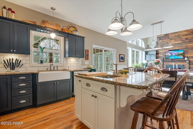 kitchen with light stone counters, decorative backsplash, a kitchen breakfast bar, and a sink