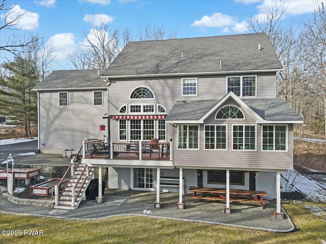 rear view of property with stairway, a patio, roof with shingles, and a wooden deck