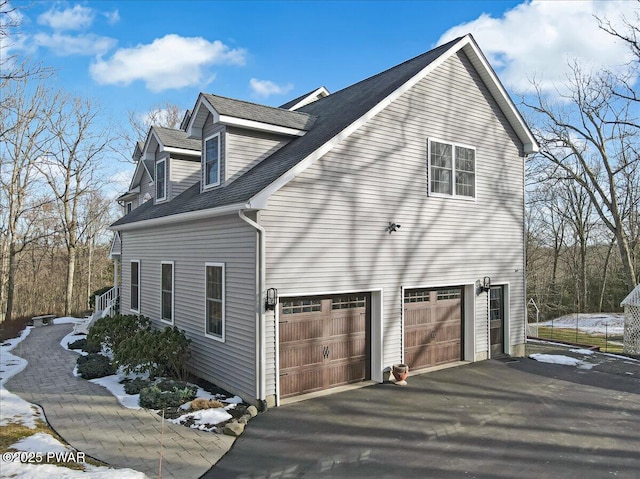 view of home's exterior with driveway, a shingled roof, and a garage