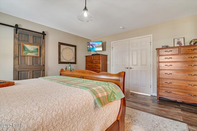 bedroom featuring a barn door, a closet, and wood finished floors