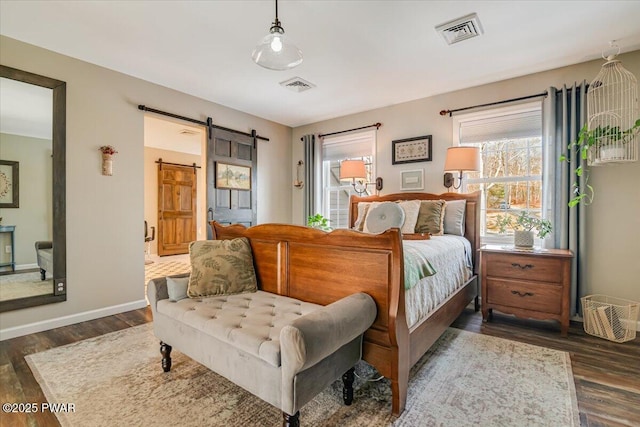 bedroom with a barn door, baseboards, visible vents, and dark wood-type flooring