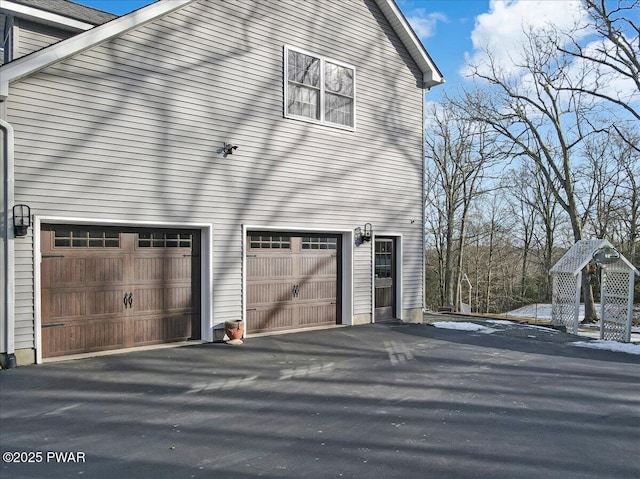 view of side of property featuring aphalt driveway and a garage