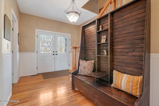 mudroom featuring light wood-type flooring, french doors, and a wainscoted wall