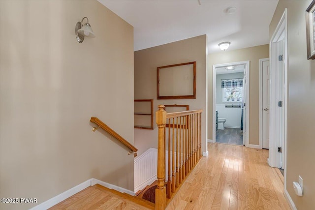 hallway with hardwood / wood-style flooring, an upstairs landing, and baseboards