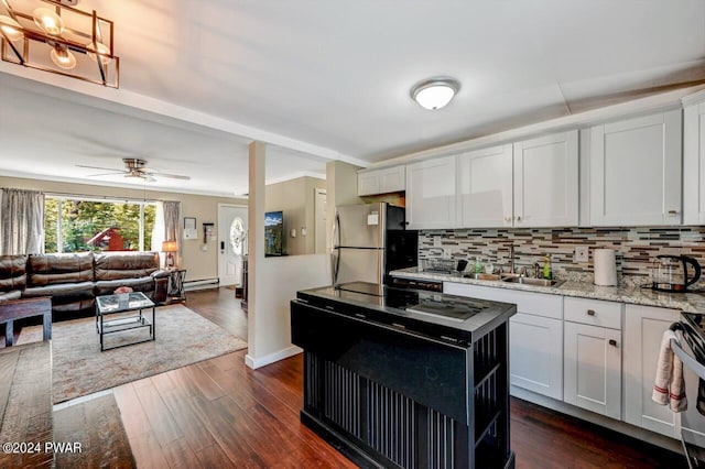 kitchen with sink, tasteful backsplash, stainless steel fridge, white cabinets, and range