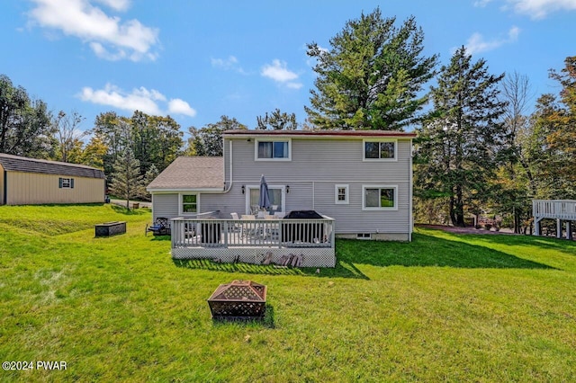 rear view of house featuring a fire pit, a yard, and a wooden deck