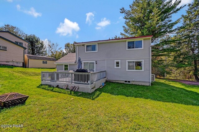 rear view of house with a fire pit, a yard, and a wooden deck