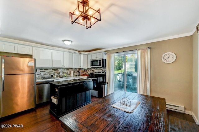 kitchen with dark wood-type flooring, white cabinets, hanging light fixtures, baseboard heating, and stainless steel appliances