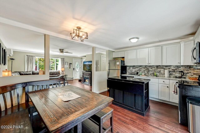 kitchen featuring dark wood-type flooring, white cabinets, ceiling fan with notable chandelier, decorative backsplash, and stainless steel appliances