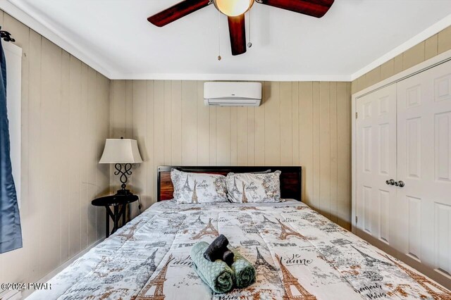 bedroom featuring a closet, an AC wall unit, ceiling fan, and wooden walls