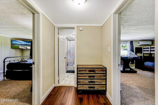 hall with wood walls, dark hardwood / wood-style floors, ornamental molding, a textured ceiling, and a wall mounted AC