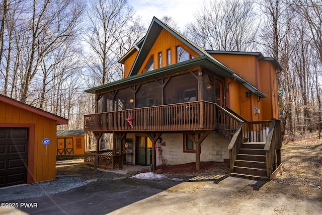 exterior space featuring an outbuilding, stairway, a patio, a shed, and a sunroom