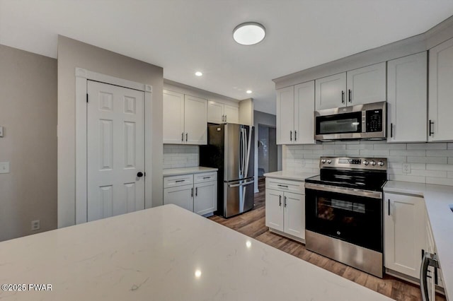 kitchen featuring stainless steel appliances, white cabinetry, dark wood-type flooring, and decorative backsplash