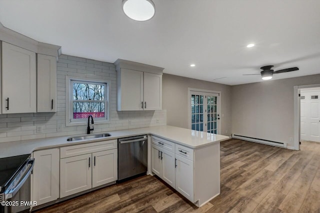 kitchen with sink, baseboard heating, white cabinetry, appliances with stainless steel finishes, and kitchen peninsula