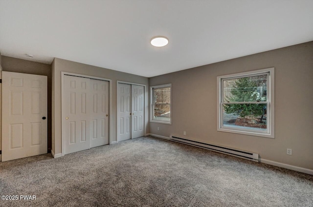 unfurnished bedroom featuring a baseboard radiator, carpet flooring, and two closets