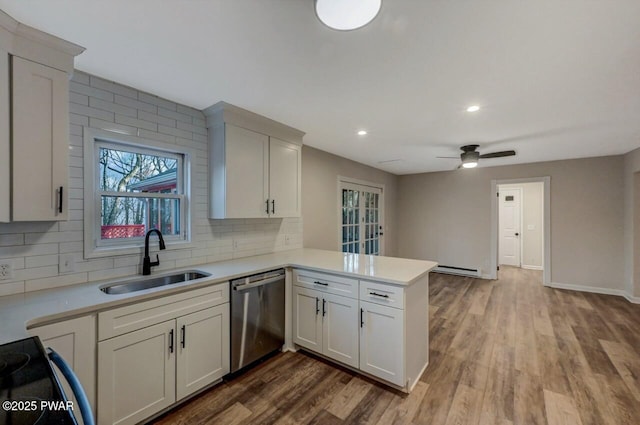 kitchen featuring dishwasher, sink, kitchen peninsula, and white cabinets