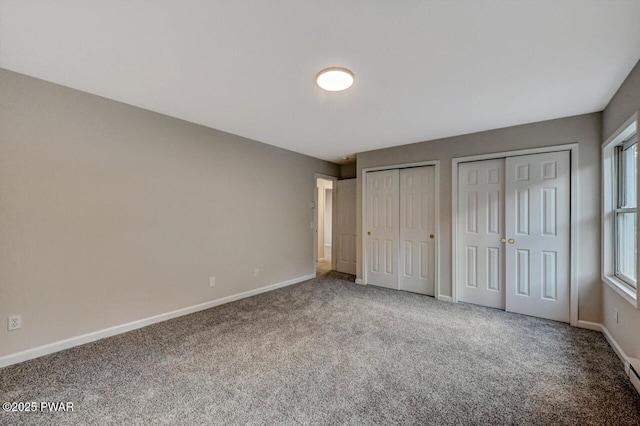 unfurnished bedroom featuring multiple closets and carpet floors