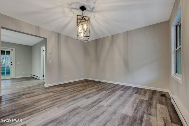 spare room with hardwood / wood-style flooring, a baseboard heating unit, and a chandelier