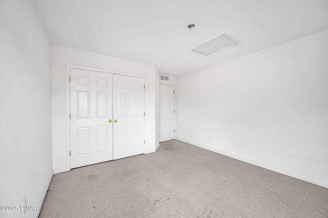 unfurnished bedroom featuring visible vents, attic access, carpet, and a closet