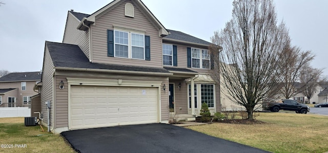 traditional-style home featuring aphalt driveway, cooling unit, an attached garage, and a front yard